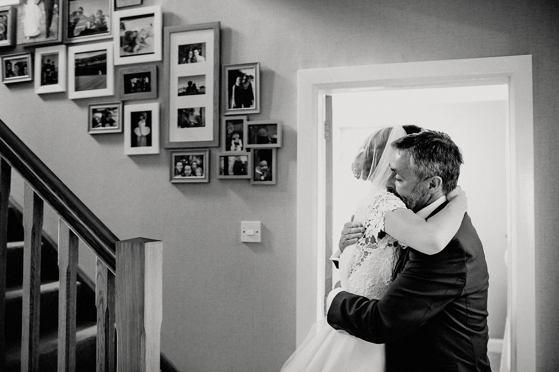 bride and dad hug at the bottom of the stairs