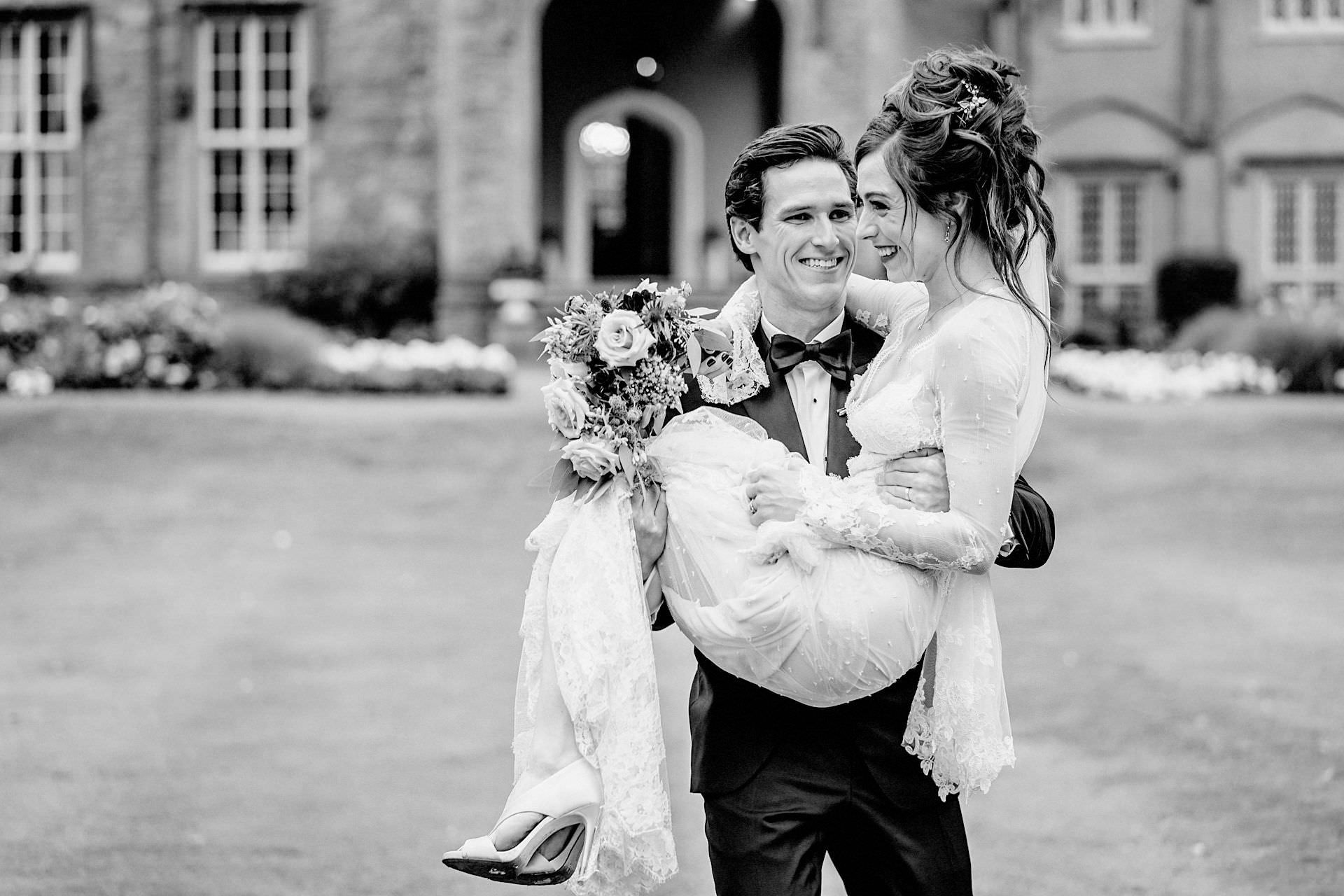 groom carrying the bride before wedding portraits on the lawn, wedding shoes, 