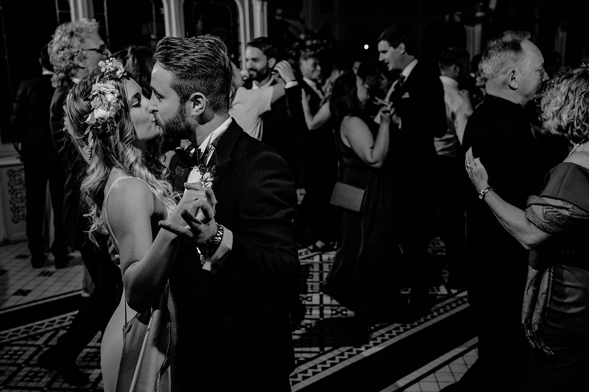 bride and groom kiss whilst the wedding goes on 